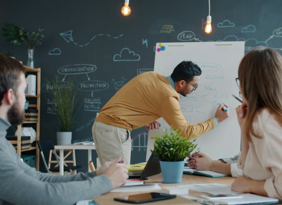 Man presenting ideas on whiteboard to colleagues